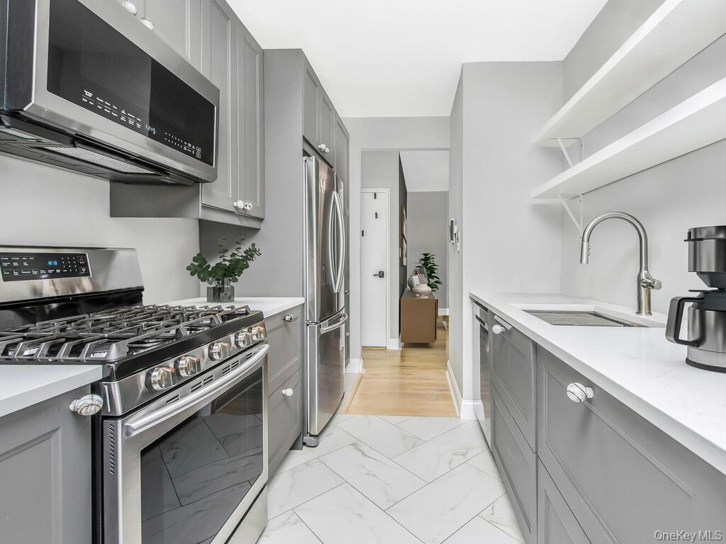 645 West 239th Street, Unit 4D Bronx, NY 10463 - Photo 7 of 13 Kitchen with stainless steel appliances, gray cabinets, light marble finish floors, and open shelves