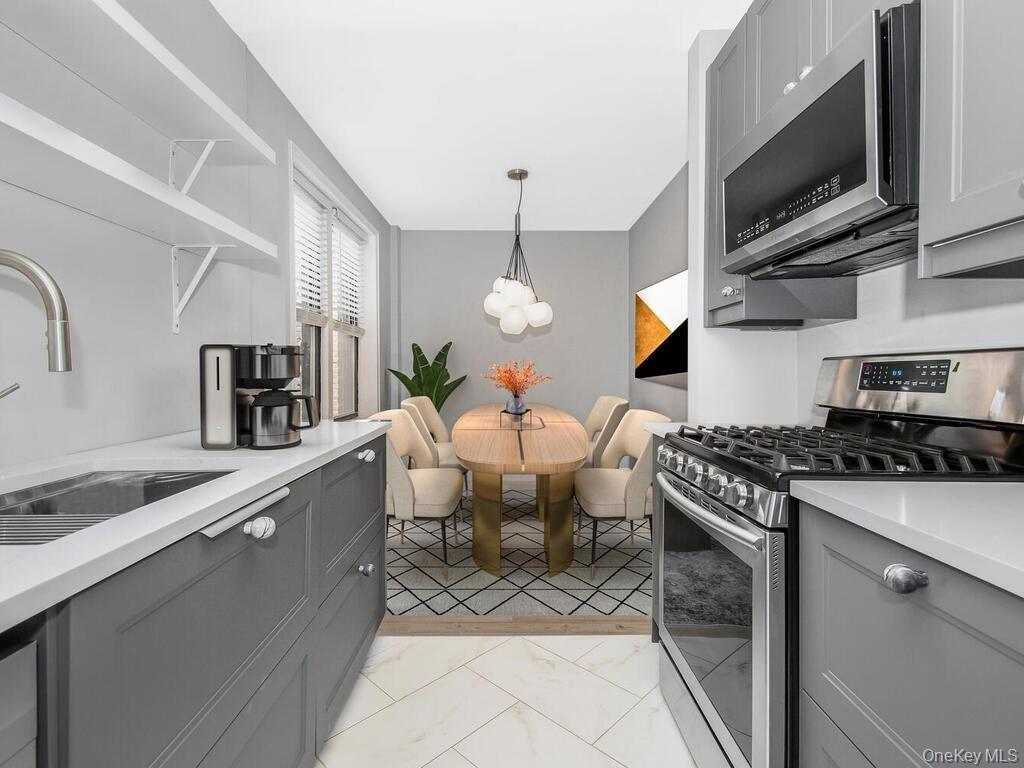 645 West 239th Street, Unit 4D Bronx, NY 10463 - Photo 8 of 13 Kitchen with gray cabinetry, stainless steel appliances, light countertops, open shelves, and light marble finish flooring