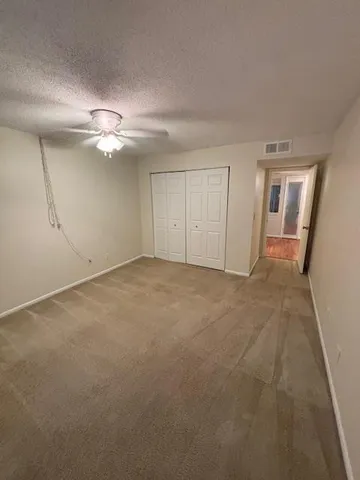 an empty room with chandelier fan and windows