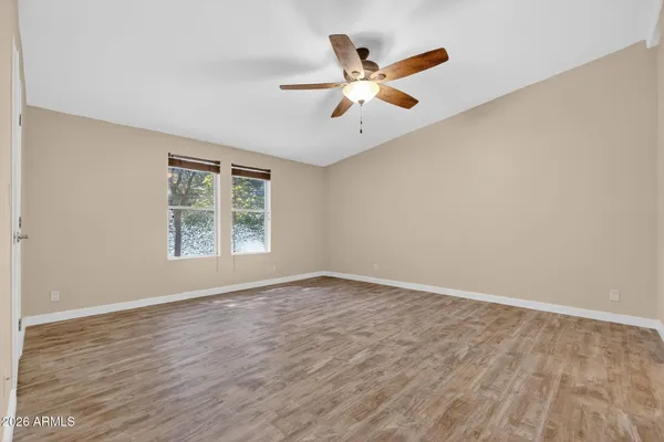 an empty room with wooden floor fan and windows