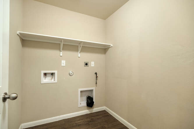 232 Voss Kyle, TX 78640 - Photo 13 of 15 Dedicated laundry area featuring a white storage shelf, white baseboards, and wood-finish flooring