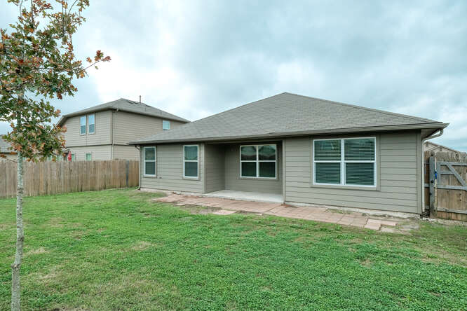 232 Voss Kyle, TX 78640 - Photo 14 of 15 Expansive backyard with a manicured lawn, a concrete patio, and a privacy fence