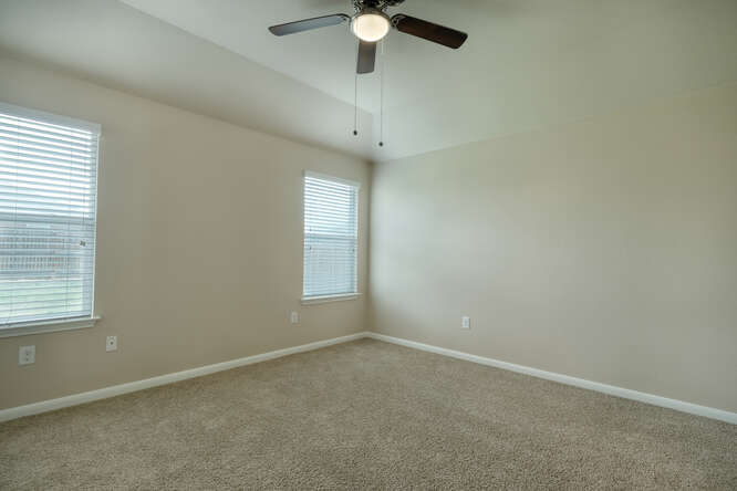 232 Voss Kyle, TX 78640 - Photo 7 of 15 Carpeted room featuring a ceiling fan with light, two windows with blinds, and neutral wall paint