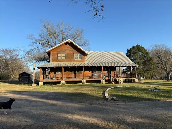 a view of a big house with a big yard and large trees