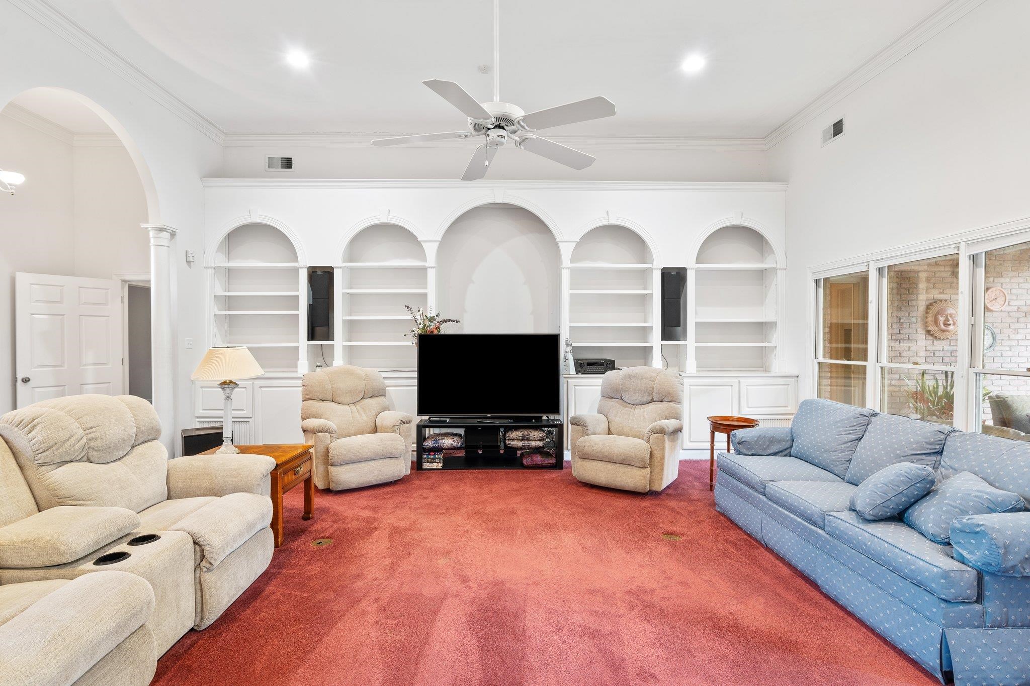 6500 State Line Road Memphis, TN 38141 - Photo 7 of 40 Living area with carpet floors, crown molding, arched walkways, built in shelves, and a ceiling fan