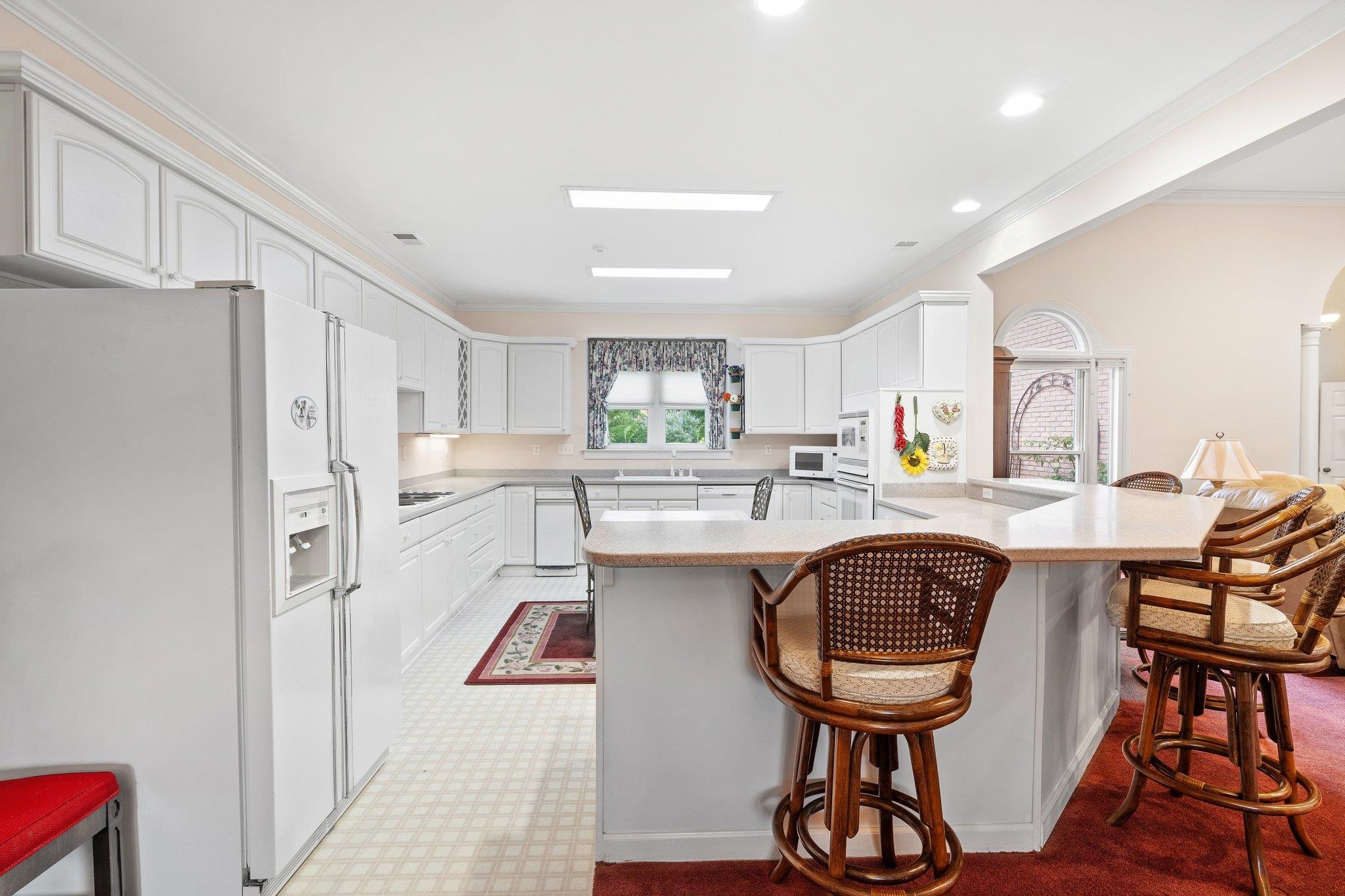 6500 State Line Road Memphis, TN 38141 - Photo 8 of 40 Kitchen featuring white appliances, a breakfast bar area, a peninsula, crown molding, and light countertops
