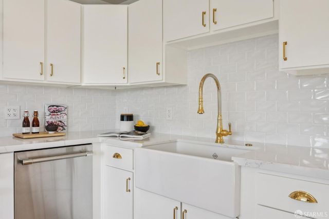 a kitchen with stainless steel appliances granite countertop a sink a refrigerator and white cabinets
