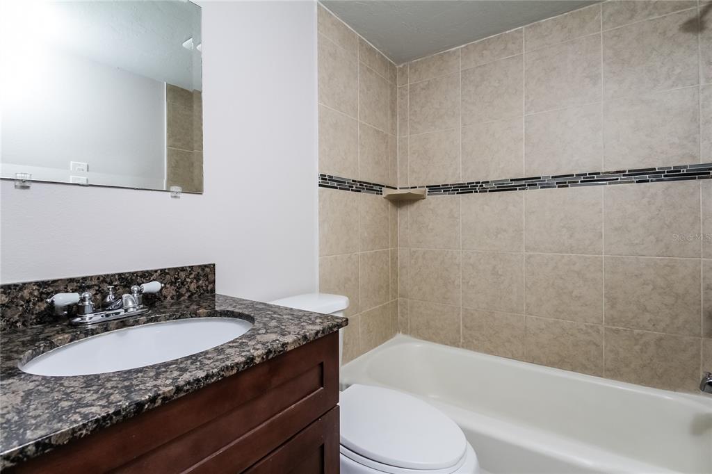 1911 3rd Avenue East Bradenton, FL 34208 - Photo 12 of 15 a bathroom with a granite countertop sink a toilet and bathtub