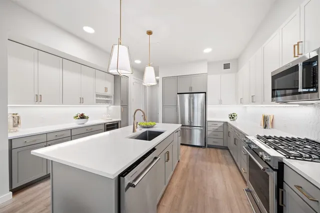 a kitchen with granite countertop a sink a counter space stainless steel appliances and cabinets