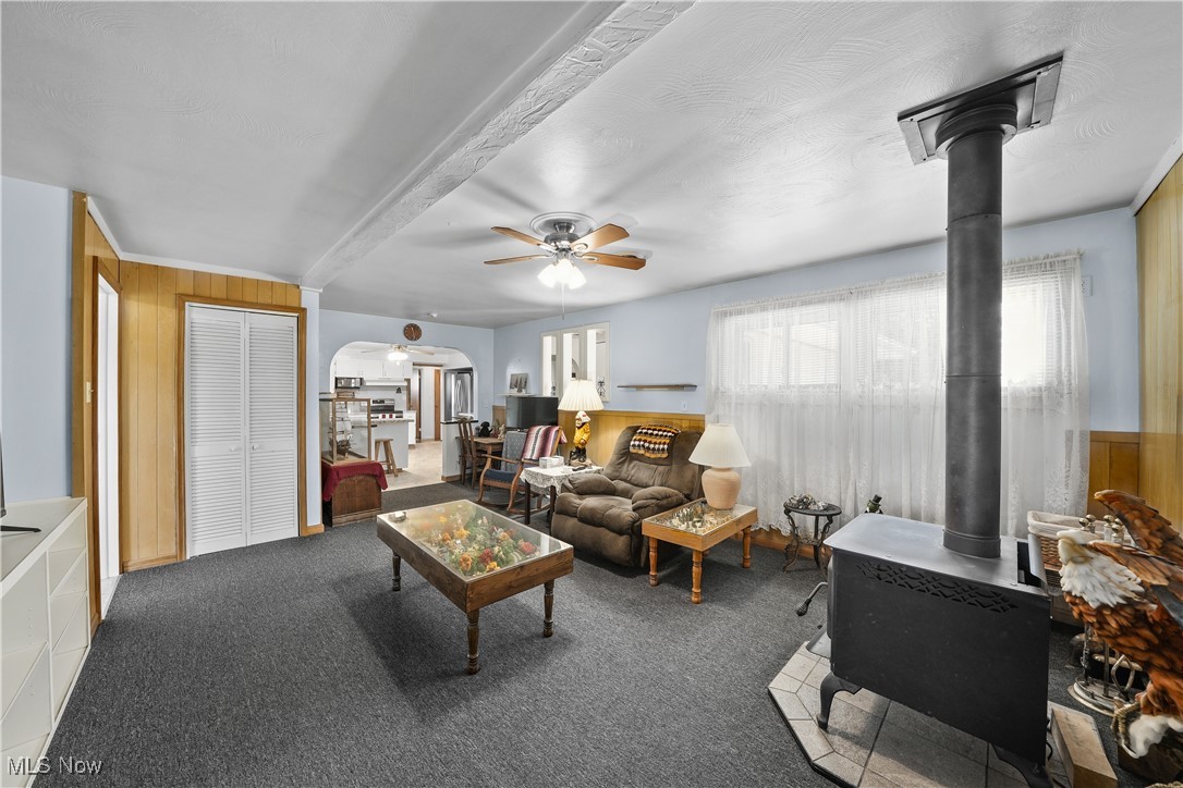 6677 Fee Road Rome, OH 44085 - Photo 24 of 39 Living room with a wood stove, ceiling fan, wood walls, and carpet floors