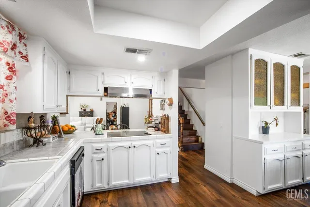 a kitchen with white cabinets and wooden floors