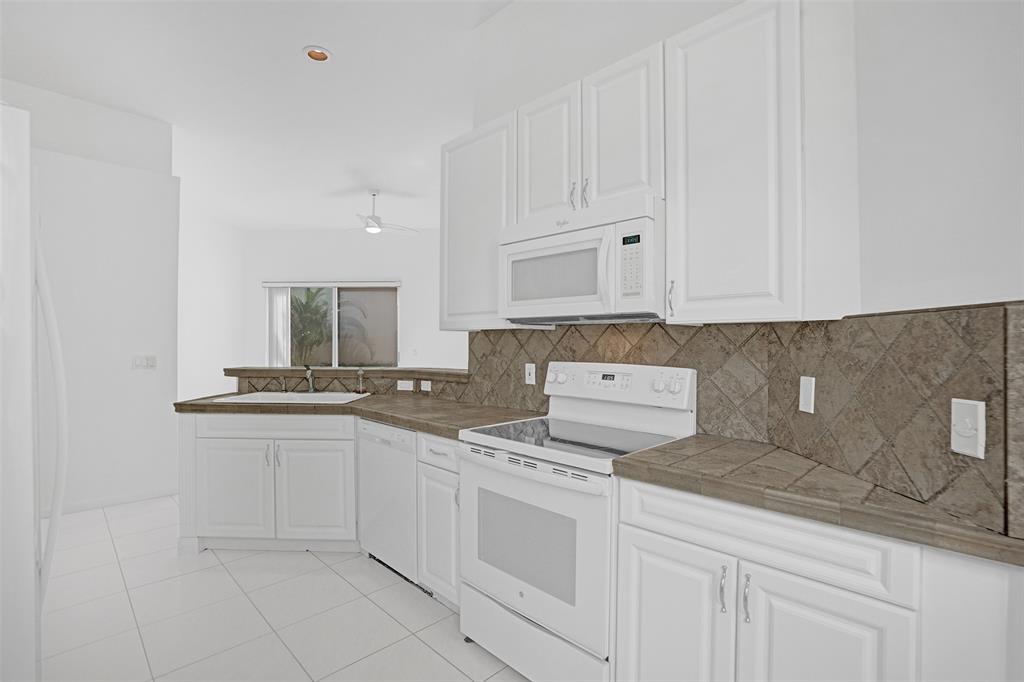 6463 Colomera Drive Boca Raton, FL 33433 - Photo 8 of 29 a kitchen with granite countertop white cabinets and white appliances