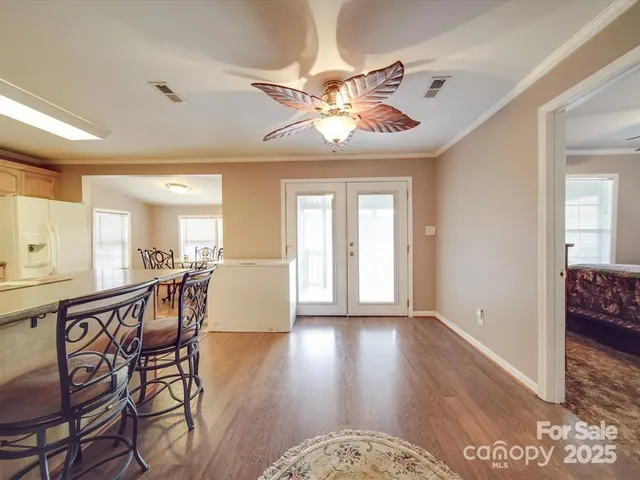 a view of a livingroom with furniture wooden floor a chandelier and windows