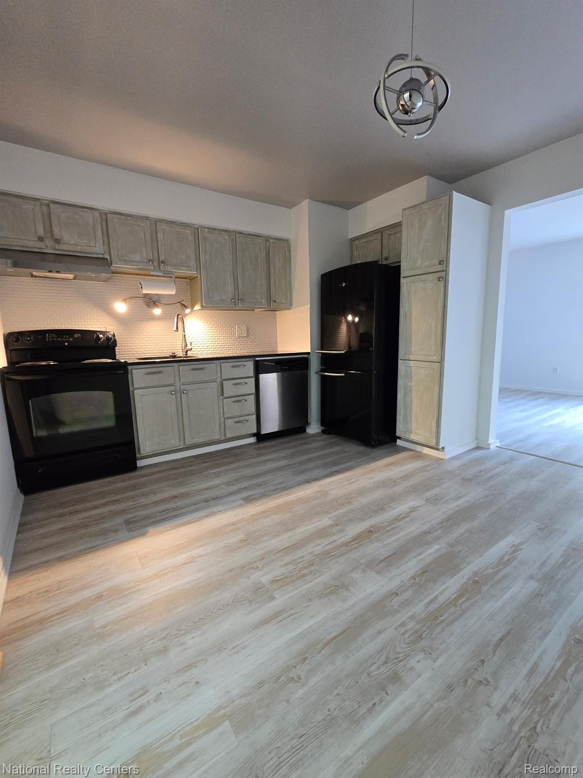616 Rickett Road, Unit 130 Brighton, MI 48116 - Photo 9 of 20 Kitchen featuring light wood-finish flooring, white hexagonal tile backsplash, stainless steel dishwasher, and a contemporary ceiling fixture