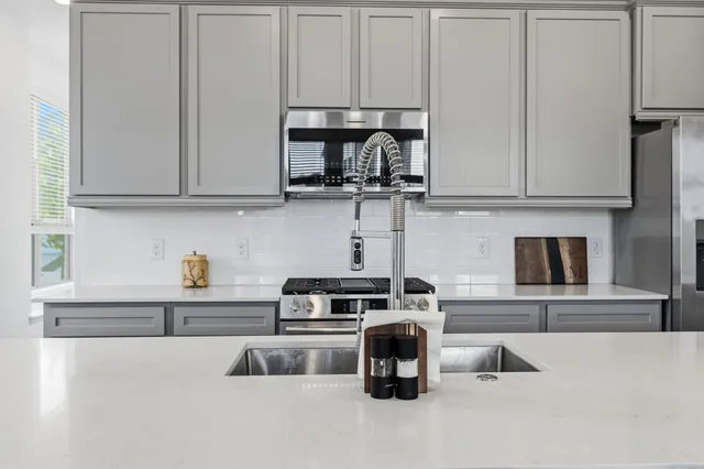 a kitchen with stainless steel appliances a sink dishwasher a stove top oven a refrigerator with wooden floor and cabinets