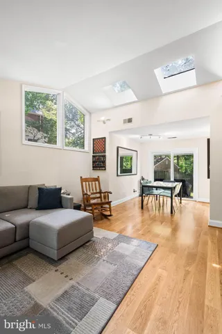 a dining room with wooden floor a chandelier a glass table and chairs