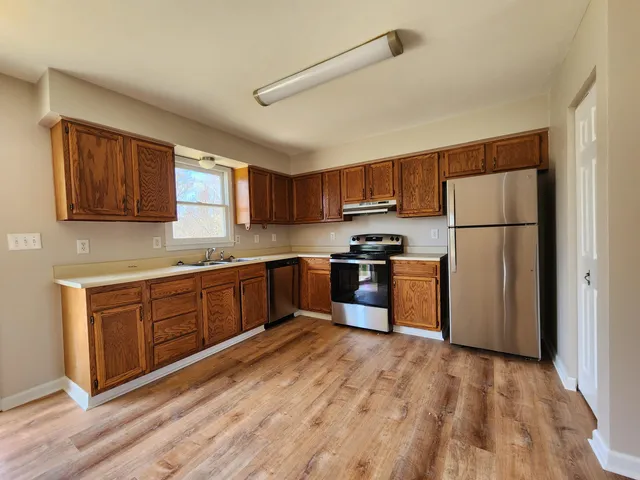 a kitchen with granite countertop a refrigerator stove top oven and sink