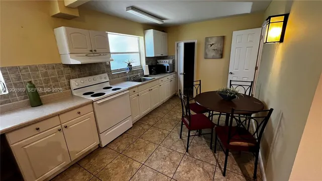 a kitchen with stainless steel appliances granite countertop white cabinets a stove top oven a sink and dishwasher