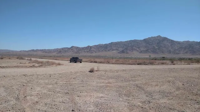 a view of a dry field with mountains in the background