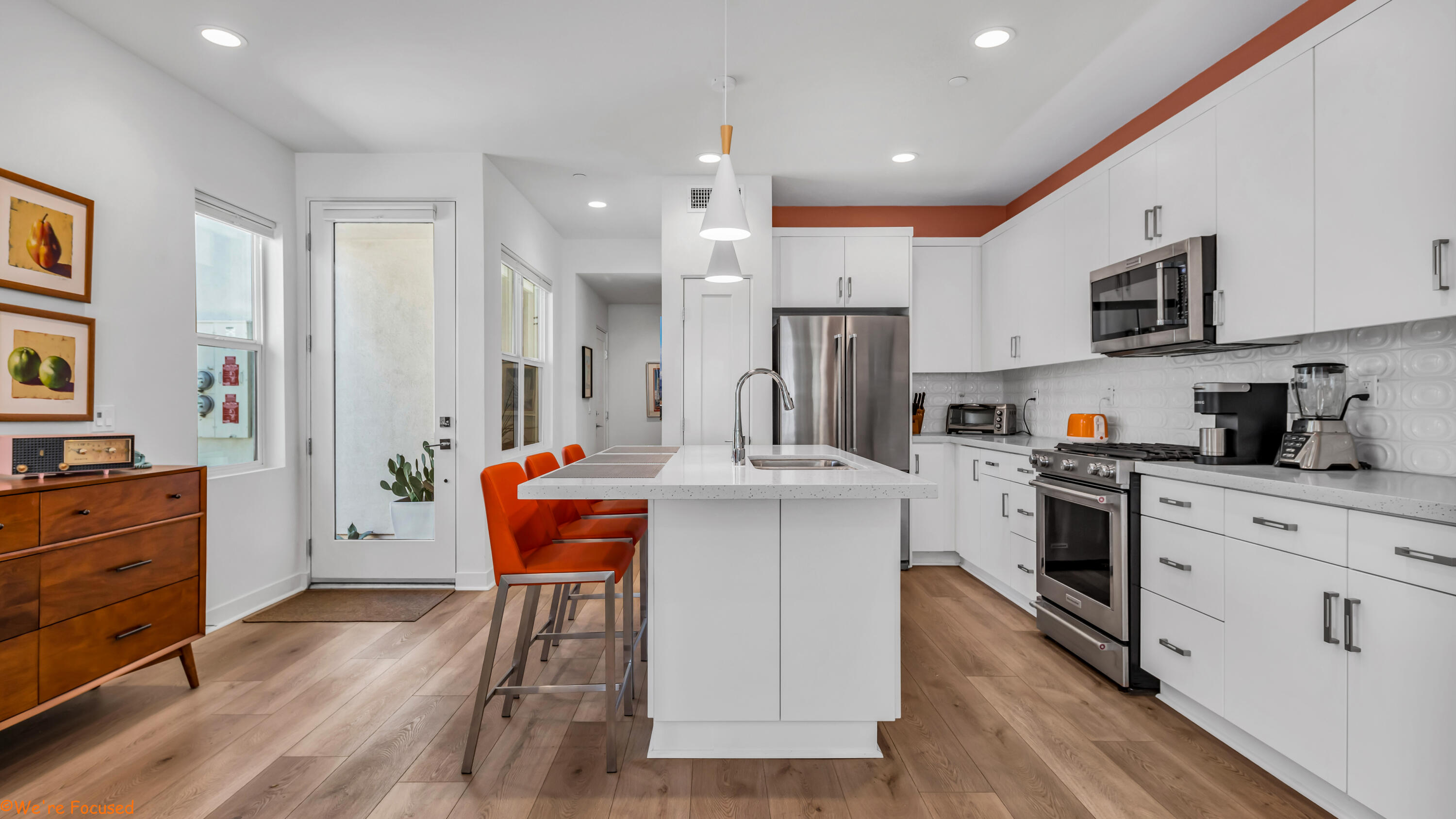 a kitchen with stainless steel appliances kitchen island granite countertop a refrigerator a stove top oven a sink dishwasher and white cabinets with wooden floor