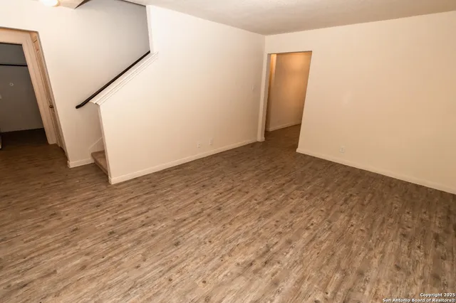 an empty room with wooden floor and stairs