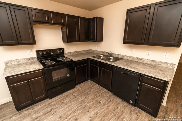 a kitchen with granite countertop stainless steel appliances a stove sink and cabinets