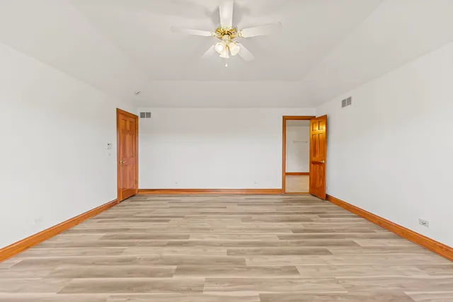 a view of an empty room with window and a ceiling fan