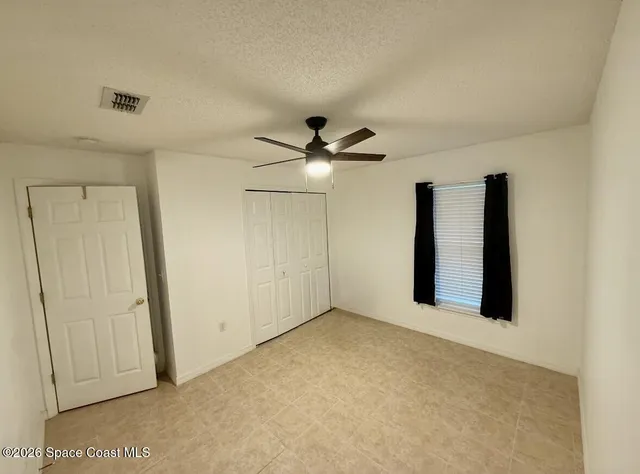 an empty room with ceiling fan and window