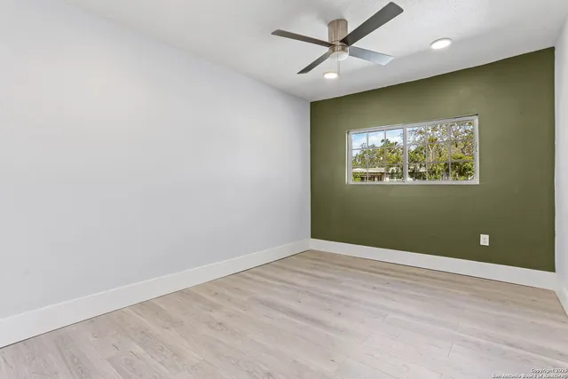 an empty room with wooden floor and ceiling fan