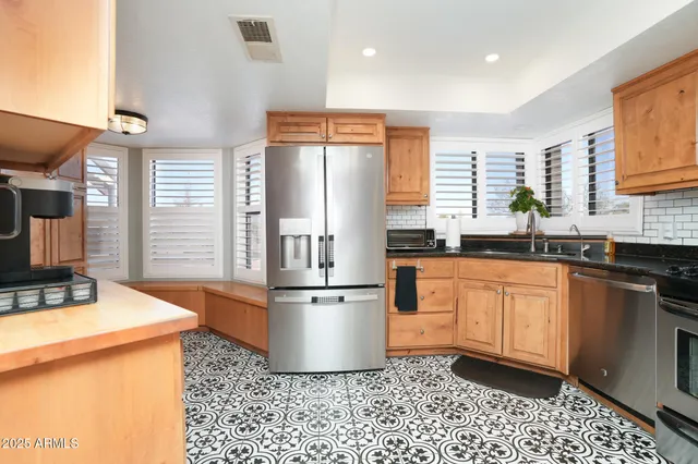 a kitchen with stainless steel appliances granite countertop a refrigerator a sink a stove a dining table and chairs