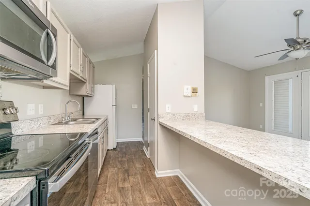 a kitchen with stainless steel appliances granite countertop a lot of counter space and wooden floor
