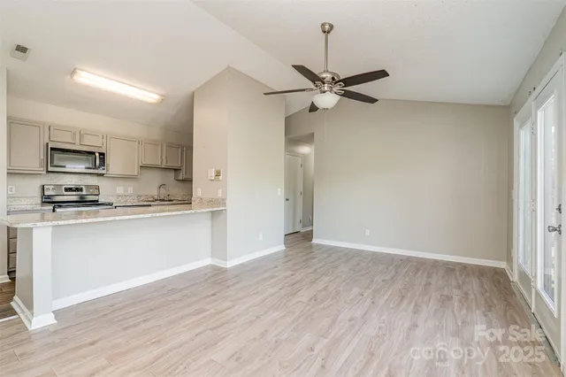a view of a kitchen with a sink a ceiling fan and wooden floor