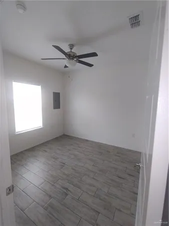 an empty room with windows and fan