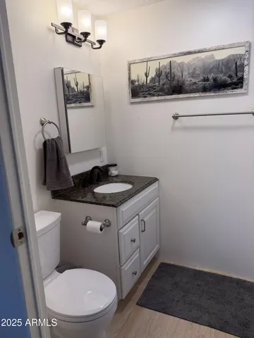 a bathroom with a granite countertop toilet and a sink