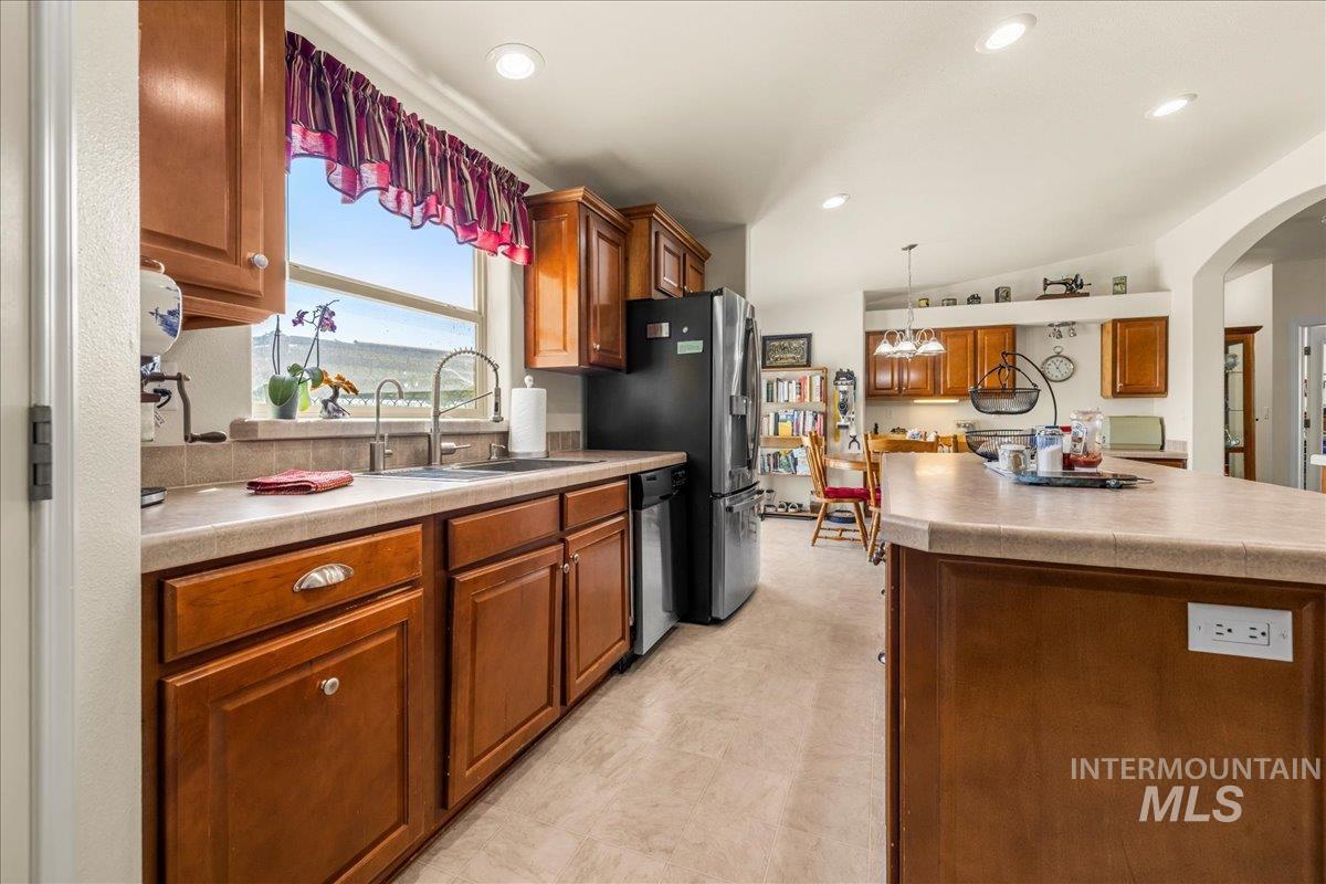 37786 Highway 78 Grand View, ID 83624 - Photo 13 of 50 Kitchen with lofted ceiling, light countertops, brown cabinetry, hanging light fixtures, and stainless steel dishwasher