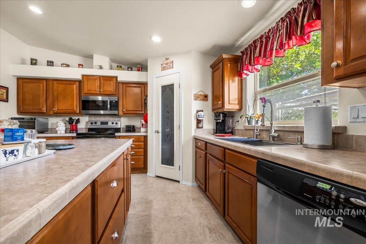 37786 Highway 78 Grand View, ID 83624 - Photo 16 of 50 Kitchen featuring appliances with stainless steel finishes, light countertops, lofted ceiling, brown cabinets, and recessed lighting