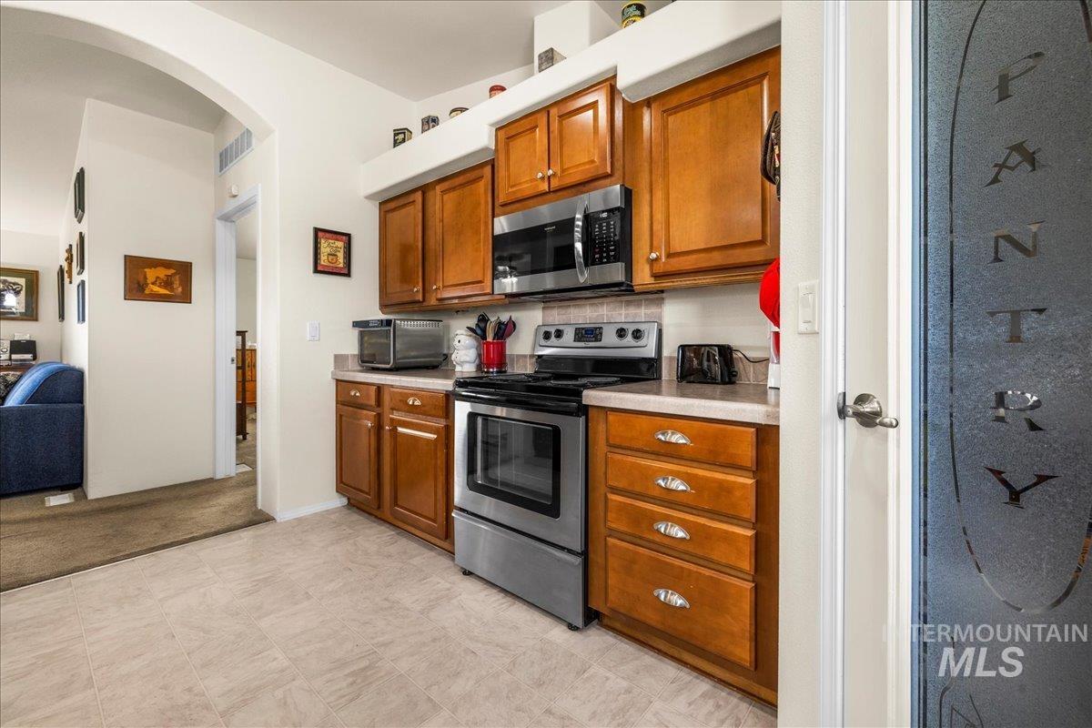 37786 Highway 78 Grand View, ID 83624 - Photo 17 of 50 Kitchen with appliances with stainless steel finishes, arched walkways, brown cabinetry, and light countertops