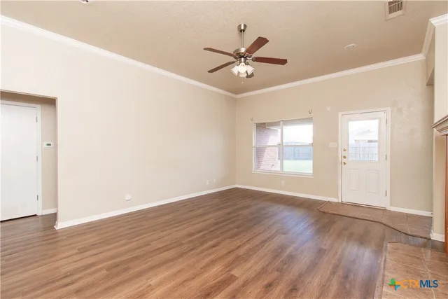 an empty room with wooden floor fan and windows