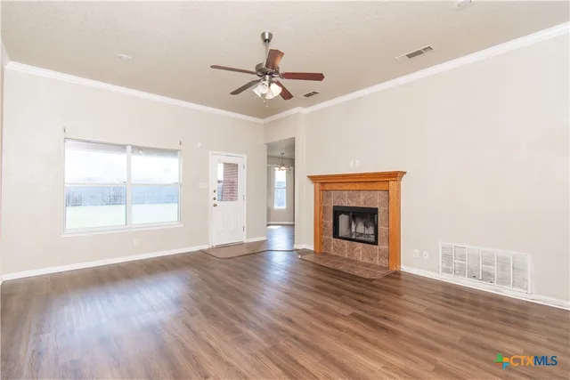 a view of an empty room with wooden floor fireplace and a window