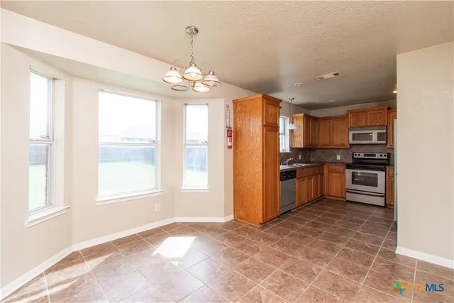 a kitchen with stainless steel appliances granite countertop a refrigerator a stove a sink dishwasher with a dining table and chairs