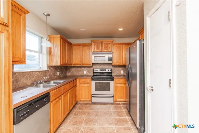 a kitchen with stainless steel appliances granite countertop a stove a sink and a refrigerator