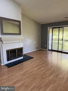 a view of empty room with wooden floor and fireplace