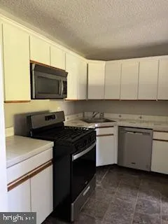 a kitchen with stainless steel appliances white cabinets and a stove top oven