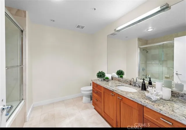 a bathroom with a granite countertop sink mirror and toilet