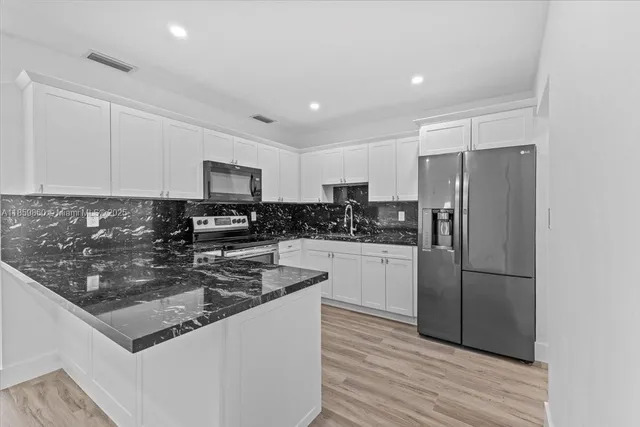 a kitchen with stainless steel appliances granite countertop a refrigerator a stove a sink and a microwave