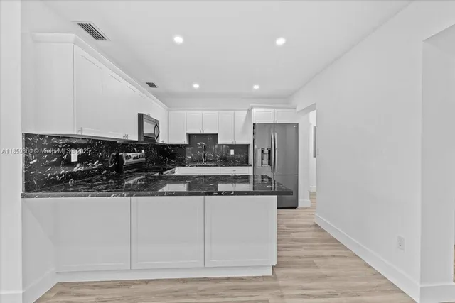 a kitchen with stainless steel appliances granite countertop a stove a sink and a refrigerator