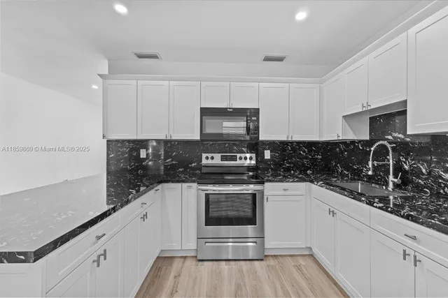 a kitchen with granite countertop a stove sink and cabinets