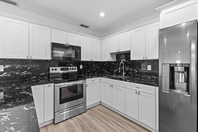 a kitchen with stainless steel appliances a sink a stove a microwave and cabinets
