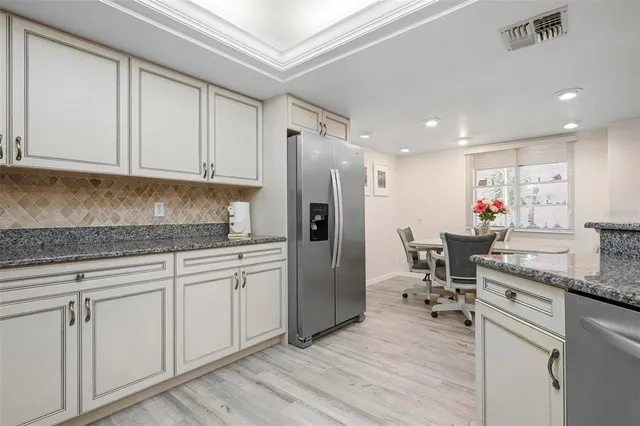 a kitchen with stainless steel appliances granite countertop a table chairs sink and cabinets
