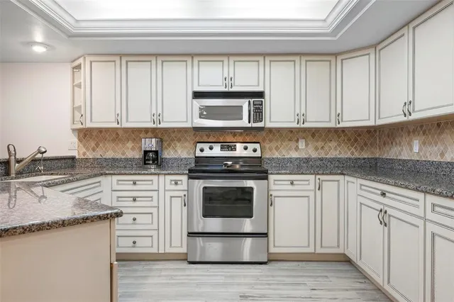 a kitchen with stainless steel appliances kitchen island granite countertop a stove a sink a dining table and chairs
